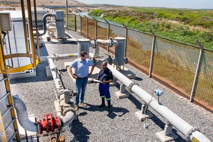 Oliver Stotko (left), an environmental engineer and head of special projects and innovation for waste services at the City of Cape Town, checks in with maintenance contractor Aaron Khethisi at the Coastal Park site. Around them is the network of pipes which feed methane from the landfill to the power plant. Photos: Jeffrey Abrahams/Ground Up Oliver Stotko (left), an environmental engineer and head of special projects and innovation for waste services at the City of Cape Town, checks in with maintenance contractor Aaron Khethisi at the Coastal Park site. Around them is the network of pipes which feed methane from the landfill to the power plant. Photos: Jeffrey Abrahams/Ground Up