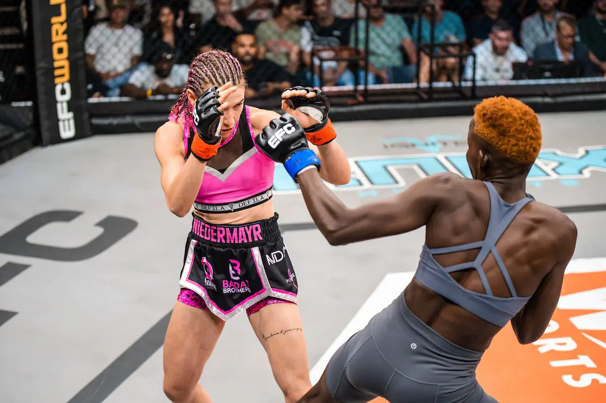 Professional female MMA fighter Ceileigh “Smiley Savage” Niedermayr (wearing pink) in a match against Uganda’s Rebecca “Warrior” Amongi. Picture: EFCWorldWide/Supplied. Professional female MMA fighter Ceileigh “Smiley Savage” Niedermayr (wearing pink) in a match against Uganda’s Rebecca “Warrior” Amongi. Picture: EFCWorldWide/Supplied.