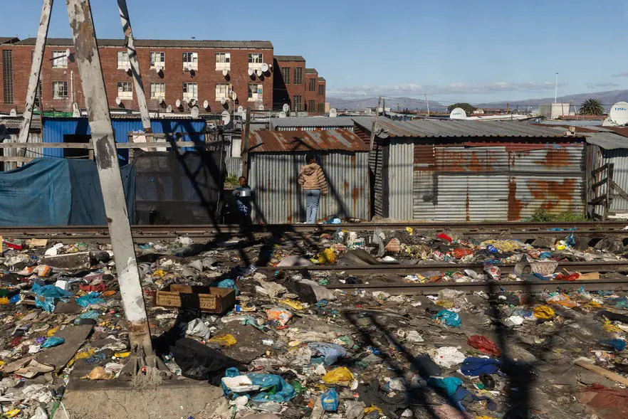 Des enfants se tiennent sur une voie ferrée sale, derrière une rangée de cabanes, alors que le train traverse des townships comme Langa et Philippi. Photo : Ashraf Hendricks/@GroundUp News Des enfants se tiennent sur une voie ferrée sale, derrière une rangée de cabanes, alors que le train traverse des townships comme Langa et Philippi. Photo : Ashraf Hendricks/@GroundUp News
