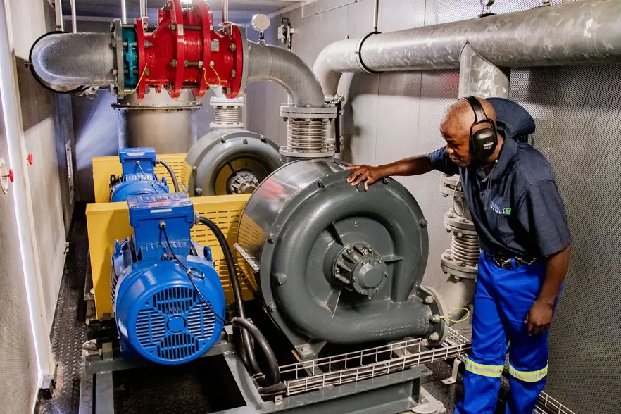 Maintenance contractor Andile Muleka with the vacuum pumps which pull the gas from the landfill wells. These pumps first first feed the gas through the extractors along the main feeder line which remove condensate. Then final extraction tales place in heat exchangers, within which chilled water from a chiller, condenses out further impurities, before driving the generators. The pumps are used alternately. Photos: Jeffrey Abrahams/Ground Up Maintenance contractor Andile Muleka with the vacuum pumps which pull the gas from the landfill wells. These pumps first first feed the gas through the extractors along the main feeder line which remove condensate. Then final extraction tales place in heat exchangers, within which chilled water from a chiller, condenses out further impurities, before driving the generators. The pumps are used alternately. Photos: Jeffrey Abrahams/Ground Up