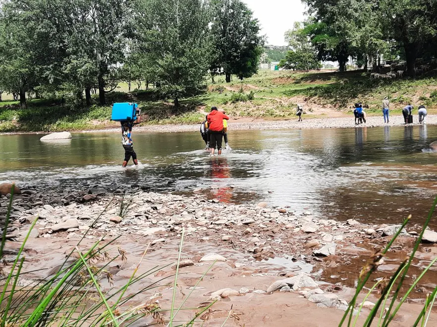 Some people pay men at the river to carry them across on their backs, charging between M20 and M40 per person. Others wade across themselves with their luggage. Picture: Sechaba Mokhethi/@GroundUp News Some people pay men at the river to carry them across on their backs, charging between M20 and M40 per person. Others wade across themselves with their luggage. Picture: Sechaba Mokhethi/@GroundUp News