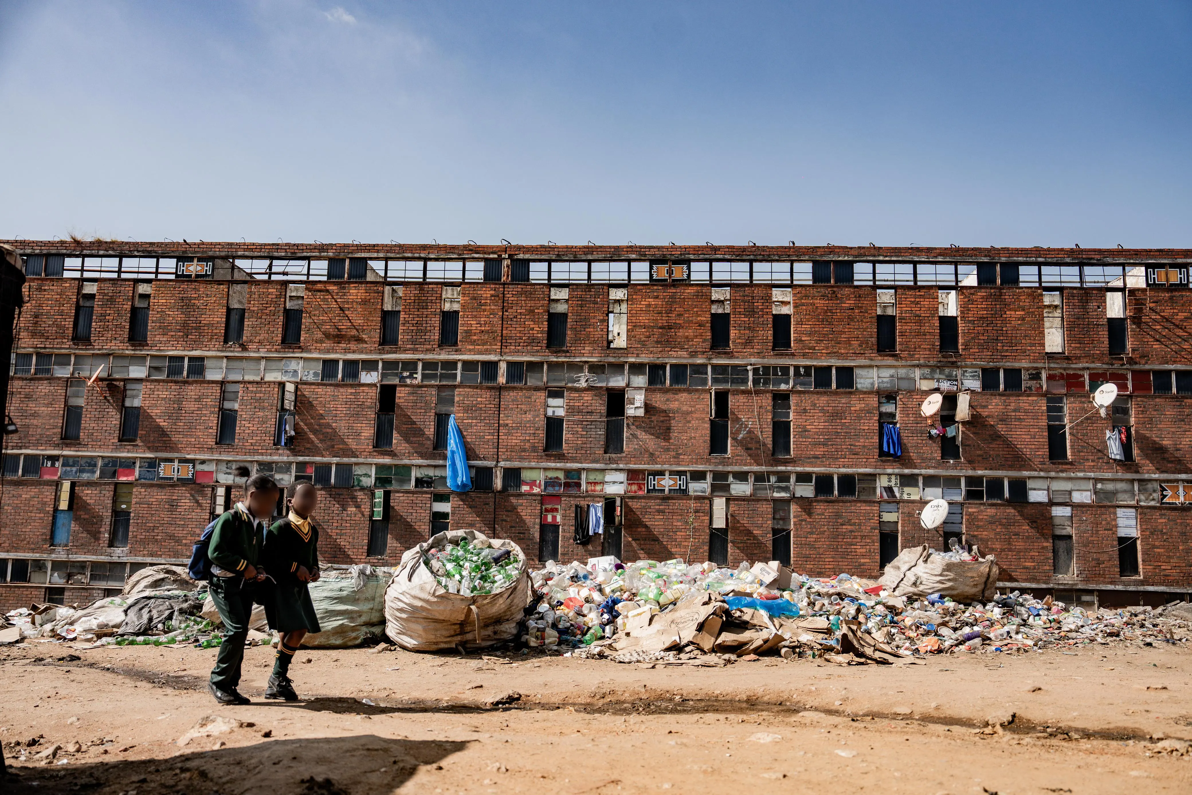 Outside the hostel, leaking sewage and scattered litter have transformed the entrance into an unofficial recycling zone. Photo: Sphamandla Dlamini/EWN Outside the hostel, leaking sewage and scattered litter have transformed the entrance into an unofficial recycling zone. Photo: Sphamandla Dlamini/EWN