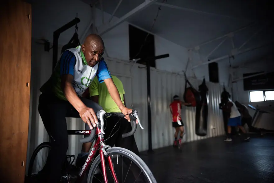 Cycling and boxing coach Luzuko Diyantyi trains on a stationary training bike. Dyantyi joined the academy in 2015 and is also responsible for the academic tutoring sessions. Picture: David Harrison/@GroundUp News Cycling and boxing coach Luzuko Diyantyi trains on a stationary training bike. Dyantyi joined the academy in 2015 and is also responsible for the academic tutoring sessions. Picture: David Harrison/@GroundUp News